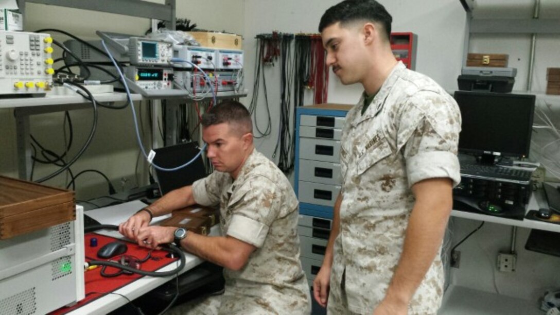SSgt Scott A. Leonardson teaches Cpl Billy A. Flores on way to use a Precise Network Analyzer. SSgt Leonardson, who works in the Ground Communications Maintenance Section of Headquarters Company, is in charge of the Calibrations section in GCMS. Being a fearless leader he is always willing to take the time to teach fellow Marines.