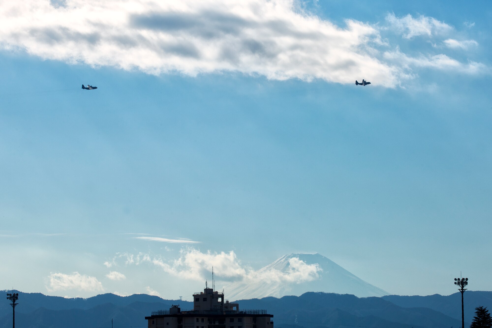 Two C-130 Hercules with the 36th Airlift Squadron fly over Yokota Air Base, Japan, during ‘Jump Week’, Jan, 7, 2015. During Jump Week, members of the 31st RQS link up with the 36th AS to maintain mission readiness and rescue tactics in preparation for real-world emergencies. (U.S. Air Force photo by Osakabe Yasuo/Released)