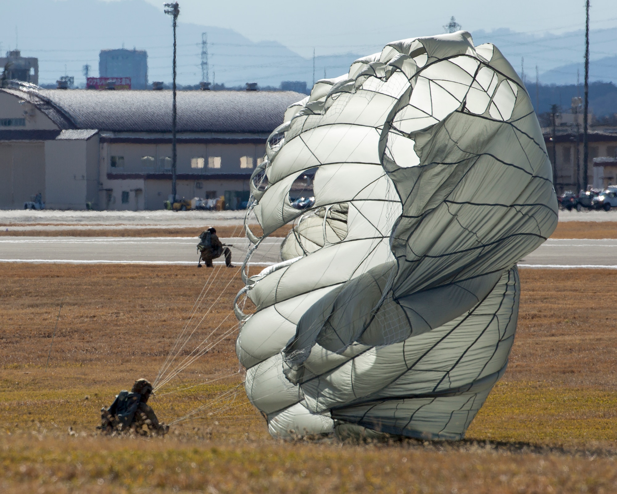 Pararescuemen from the 31st Rescue Squadron touch down in a landing zone at Yokota Air Base, Japan, Jan. 7, 2015 during ‘Jump Week’. During Jump Week, members of the 31st RQS link up with the 36th AS to maintain mission readiness and rescue tactics in preparation for real-world emergencies. (U.S. Air Force photo by Osakabe Yasuo/Released)