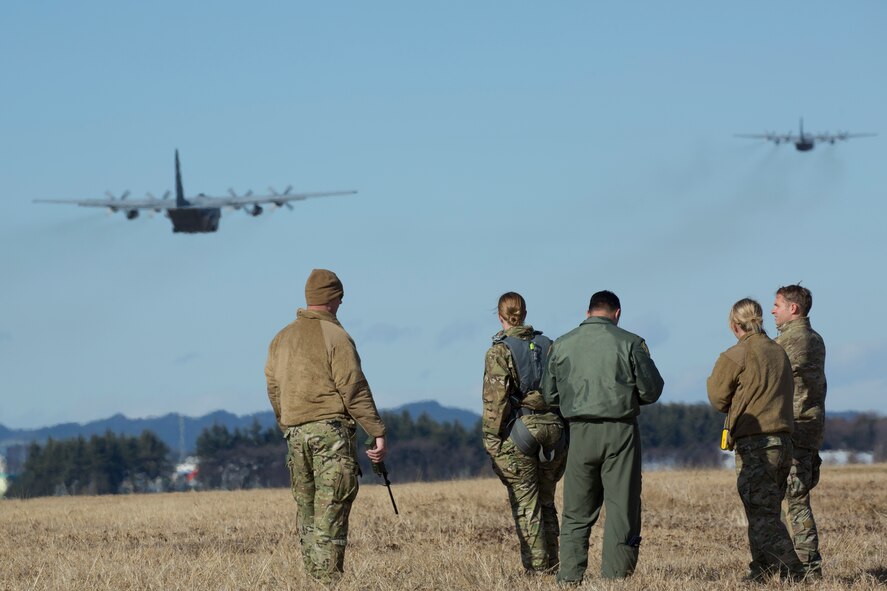 Airmen of the 31st Rescue Squadron and 36th Airlift Squadron observe two C-130 Hercules take off at a drop zone at Yokota Air Base, Japan, Jan. 7, 2015. The two squadrons maintain mission readiness for aircrew and pararescuemen. (U.S. Air Force photo by Osakabe Yasuo/Released) 
