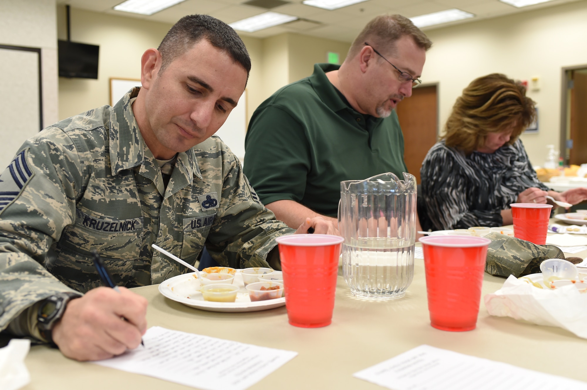 Chief Master Sgt. Brian Kruzelnick, 460th Space Wing command chief, left; R. Chris Williams, 460th Space Wing Inspector General exercise director, center; and Gretchen Meyers, 460th Space Wing Plans and Programs program analyst, right, take notes on each chili they taste as official chili judges during the chili cook-off held at the Buckley Chapel Jan. 7, 2015, on Buckley Air Force Base, Colo. Categories for judging included red, green, white, vegetarian, hot and overall chili, with each winner receiving a $20 gift card. (U.S. Air Force photo by Airman 1st Class Samantha Saulsbury/Released)