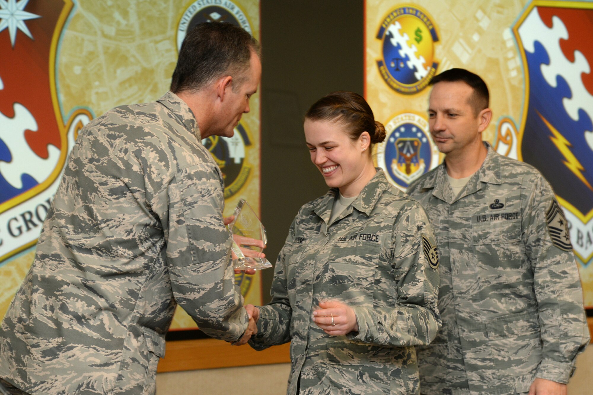 Col. Michael A. Vogel, 66th Air Base Group commander, and Hanscom Air Force Base Command Chief Master Sgt. Craig Poling, presents the NCO of the Quarter trophy to Staff Sgt. Emma F. Byrne, 66th Medical Squadron Health Services Management specialist, during the group’s fourth quarter awards ceremony at the Hanscom Conference Center, Jan. 7. The group recognized 10 military and civilian personnel and one team for exceptional performance through October to December 2014 during the ceremony. (U.S. Air Force photo by Linda LaBonte Britt)