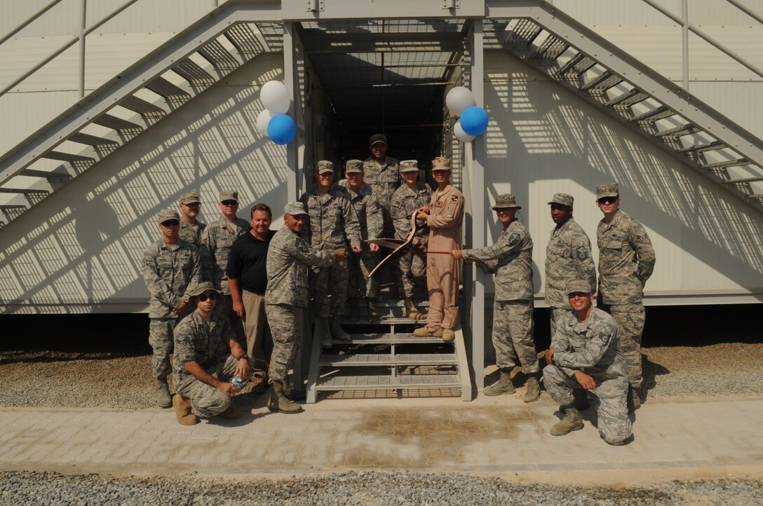 Members of the Air Expeditionary Wing stand with 
Brig. Gen. John T. Quintas, Air Expeditionary Wing commander, Chief Master Sgt. Samer Alkhoury, AEW command chief, and members of the AEW team prepare to cut the ribbon at the grand opening ceremony of the new re-locatable billets Oct. 13, 2014, at an undisclosed location in Southwest Asia.  (U.S. Air Force photo by Senior Master Sgt. Carrie Hinson/Released)
