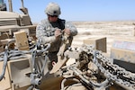 Spc. Benjamin Peterson with the maintenance platoon, 21tth Engineer Company, South Dakota Army National Guard, works to recover a set of mine rollers damaged by an improvised explosive device (IED) during a route clearance mission here April 5.