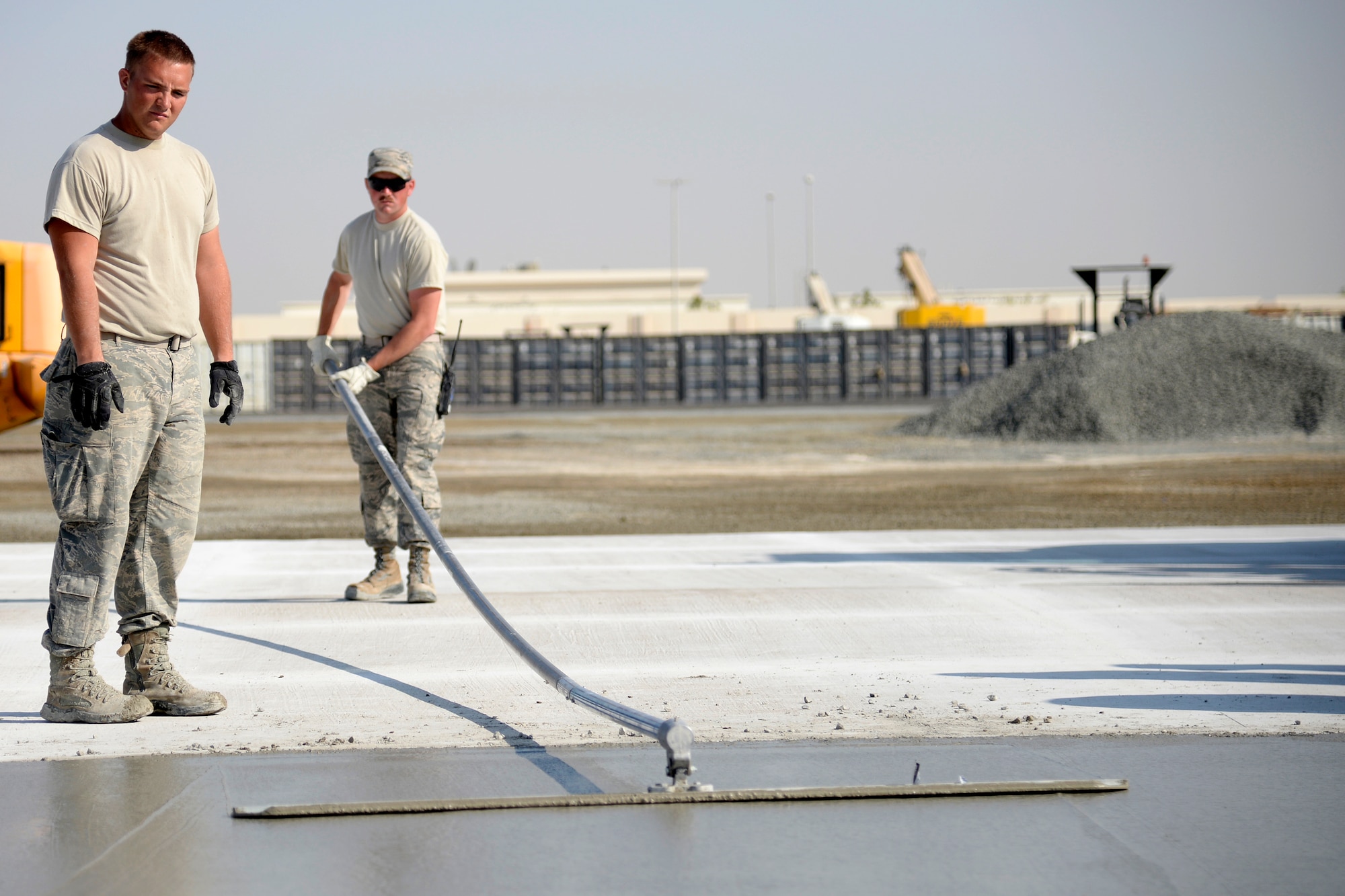 Senior Airman Dillon, Expeditionary Civil Engineer Squadron watches as Tech. Sgt. Ronald, ECES, works on a new concrete pad at the Australian beddown site on an undisclosed location in Southwest Asia Oct. 30, 2014. Airmen with the ECES worked side-by-side with their Australian counterparts as they collectively constructed a beddown site from the ground up. (U.S. Air Force photo/Tech. Sgt. Marie Brown)