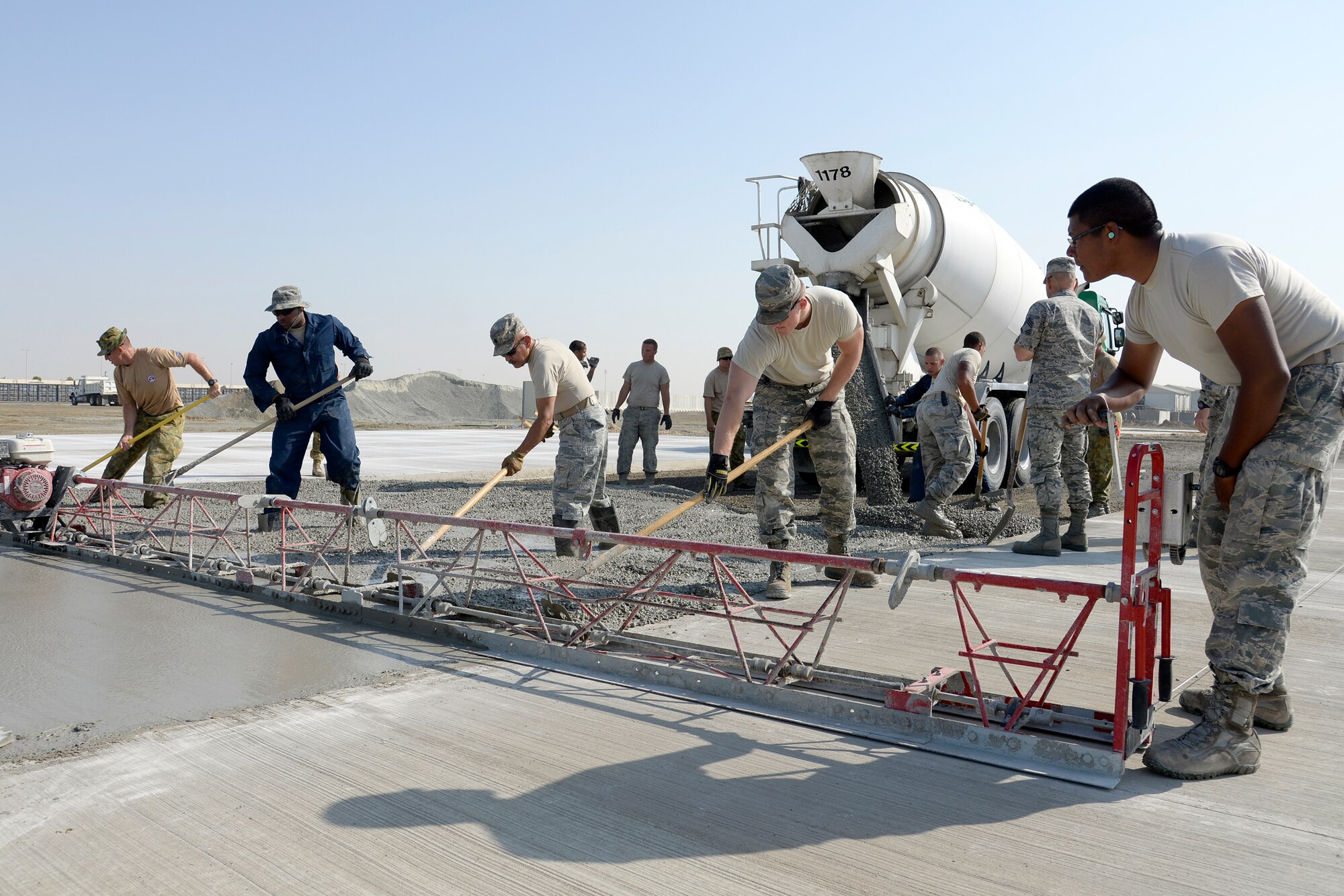 Airmen with the Expeditionary Civil Engineer Squadron work side-by-side with Australians from the Royal Australian Air Force Air Task Group to lay concrete at the new Australian beddown site at an undisclosed location in Southwest Asia Oct. 30, 2014. Approximately nine members of the RAAF Air Task Group integrated with Airmen in the ECES where they were able to learn different styles of training. (U.S. Air Force photo/Tech. Sgt. Marie Brown)