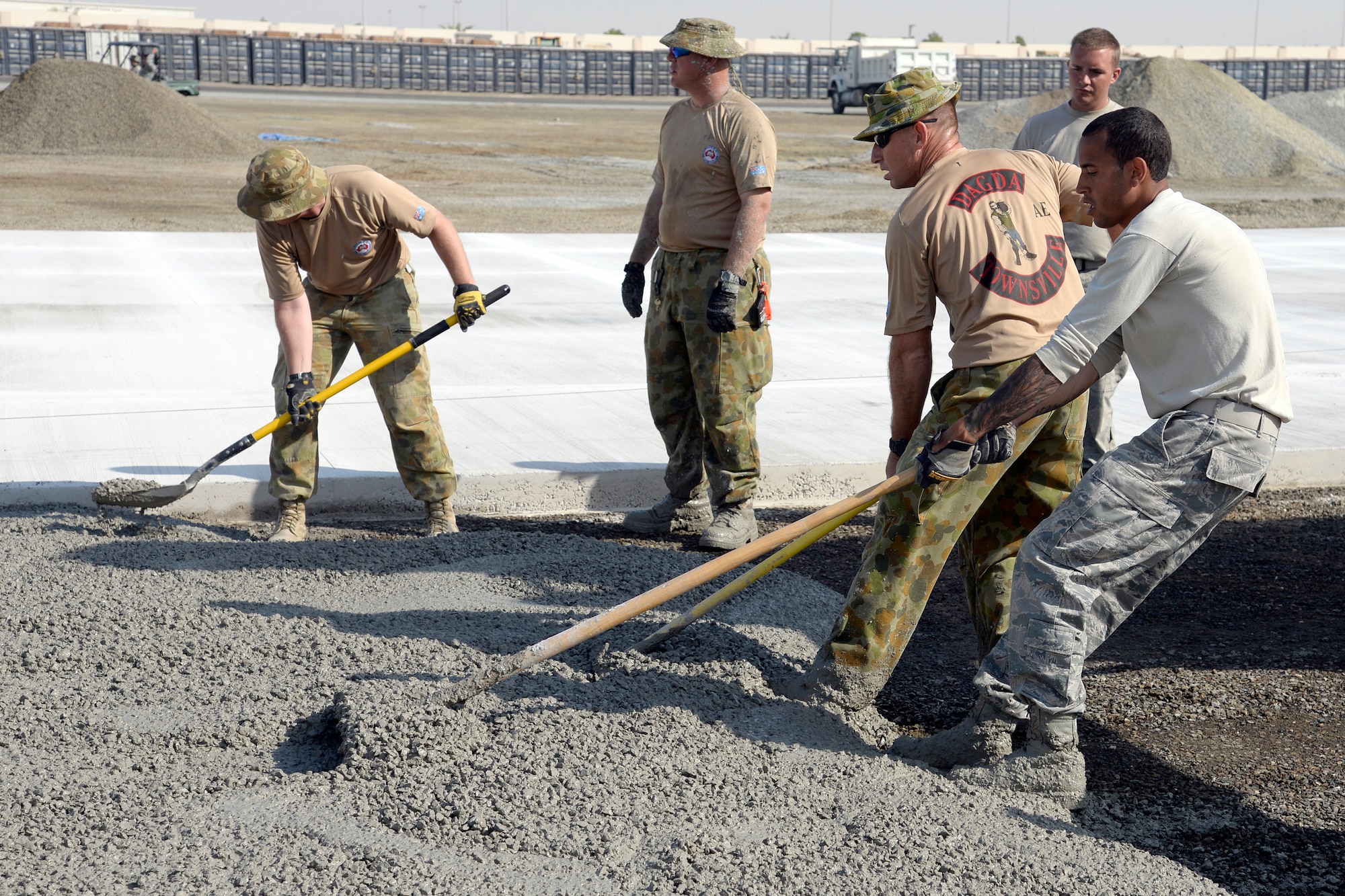 Airmen with the Expeditionary Civil Engineer Squadron work side-by-side with Australians from the Royal Australian Air Force Air Task Group to lay concrete at the new Australian beddown site on an undisclosed location in Southwest Asia Oct. 30, 2014. Airmen with the ECES worked side-by-side with their Australian counterparts as they collectively constructed a beddown site from the ground up. (U.S. Air Force photo/Tech. Sgt. Marie Brown)