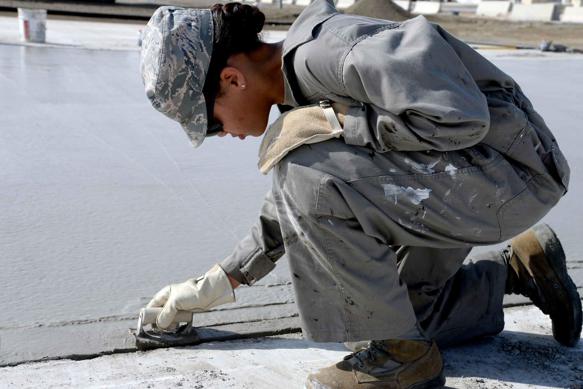 Senior Airman Any, Expeditionary Civil Engineer Squadron structural journeyman, smoothes the edges of fresh laid concrete at the Australian beddown site on an undisclosed location in Southwest Asia Oct. 30, 2014. Airmen with the ECES worked side-by-side with their Australian counterparts to construct 35 tents. (U.S. Air Force photo/Tech. Sgt. Marie Brown)