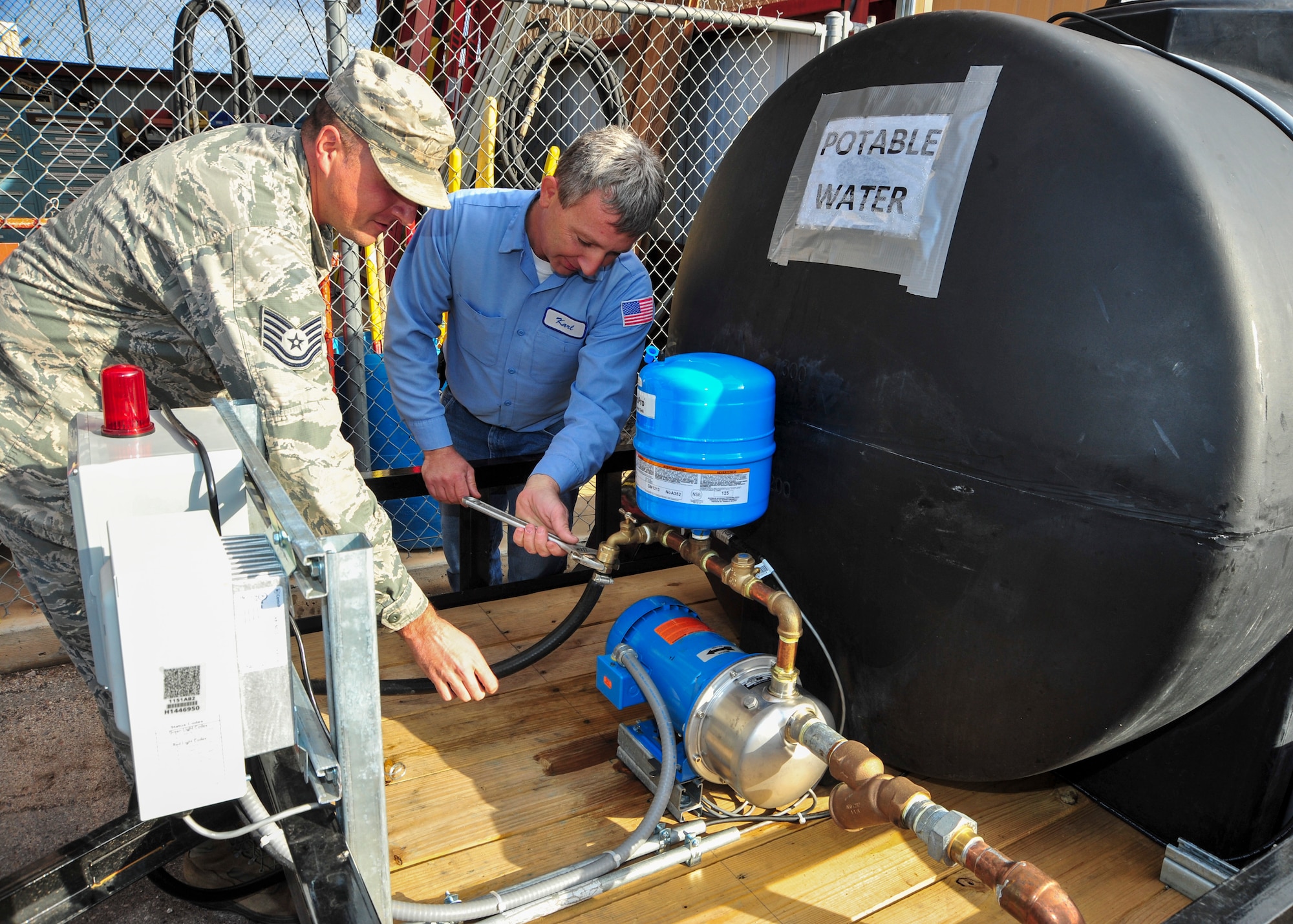 U.S. Air Force Tech. Sgt. Mike Golubski, 355th Civil Engineer Squadron water fuels system maintenance craftsman, and Karl Blair, 355th CES journeyman utility man, connect a hose to a portable water system at Davis-Monthan Air Force Base, Ariz., Jan. 9, 2015.  Blair designed and developed the system which allows the WFSM team to supply a building with a continuous, uninterrupted potable water supply during emergency water outages.  (U.S. Air Force photo by Airman 1st Class Chris Massey)