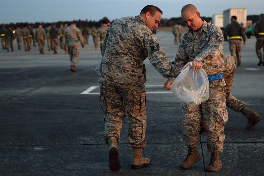 U.S. Air Force Tech. Sgt. Jeremy Hobbs, 347th Operations Support Squadron resource advisor, right, collects debris from Master Sgt. Mike Weidner, 347th OSS first sergeant, during the foreign object debris walk Jan. 5, 2015, at Moody Air Force Base, Ga. The purpose of a FOD walk is to clear the flightline of anything that could damage aircraft. (U.S. Air Force photo by Airman 1st Class Kathleen D. Bryant/Released)