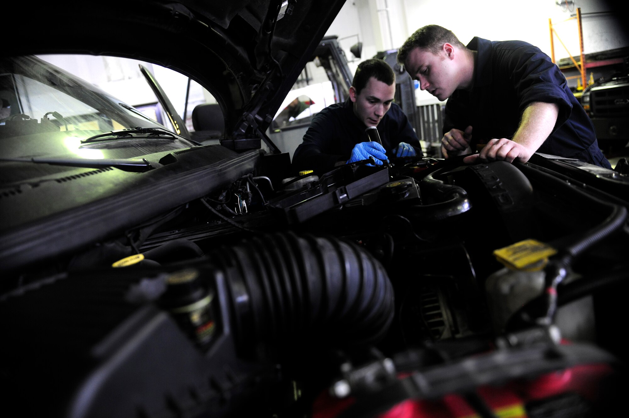 (From left)U.S. Air Force Senior Airman Benjamin Blaes and Airman 1st Class Jesse Holmgren, 31st Logistics Readiness Squadron vehicle maintenance flight technicians, repair a vehicle, Jan. 7, 2015, at Aviano Air Base, Italy. The vehicle maintenance flight is responsible for the inspection, repairing, modifying and accounting for all government-owned vehicles on base.  (U.S. Air Force photo by Staff Sgt. Evelyn Chavez/Released)