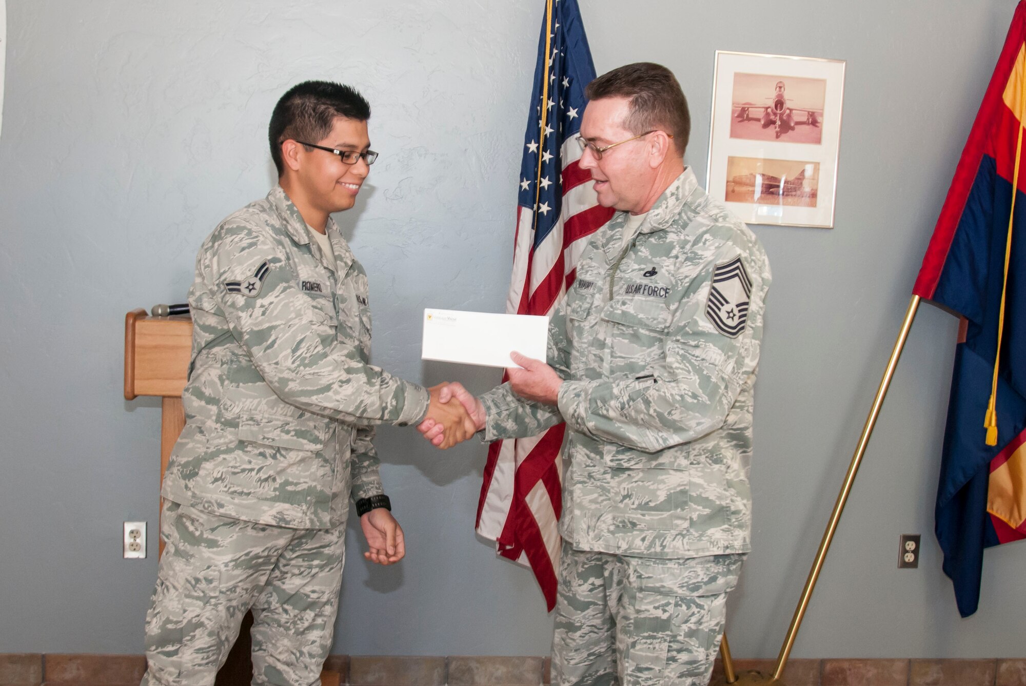 Airman 1st Class Israel Romero receives a check for $500 from Chief Master Sgt. Vandervort here January 5. (U.S. Air National Guard Photo by 2nd Lt. Lacey Roberts/Released)