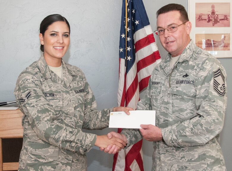 Airman 1st Class Jacqueline Ochoa receives a check for $500 from Chief Master Sgt. Vandervort here January 5. (U.S. Air National Guard Photo by 2nd Lt. Lacey Roberts/Released)