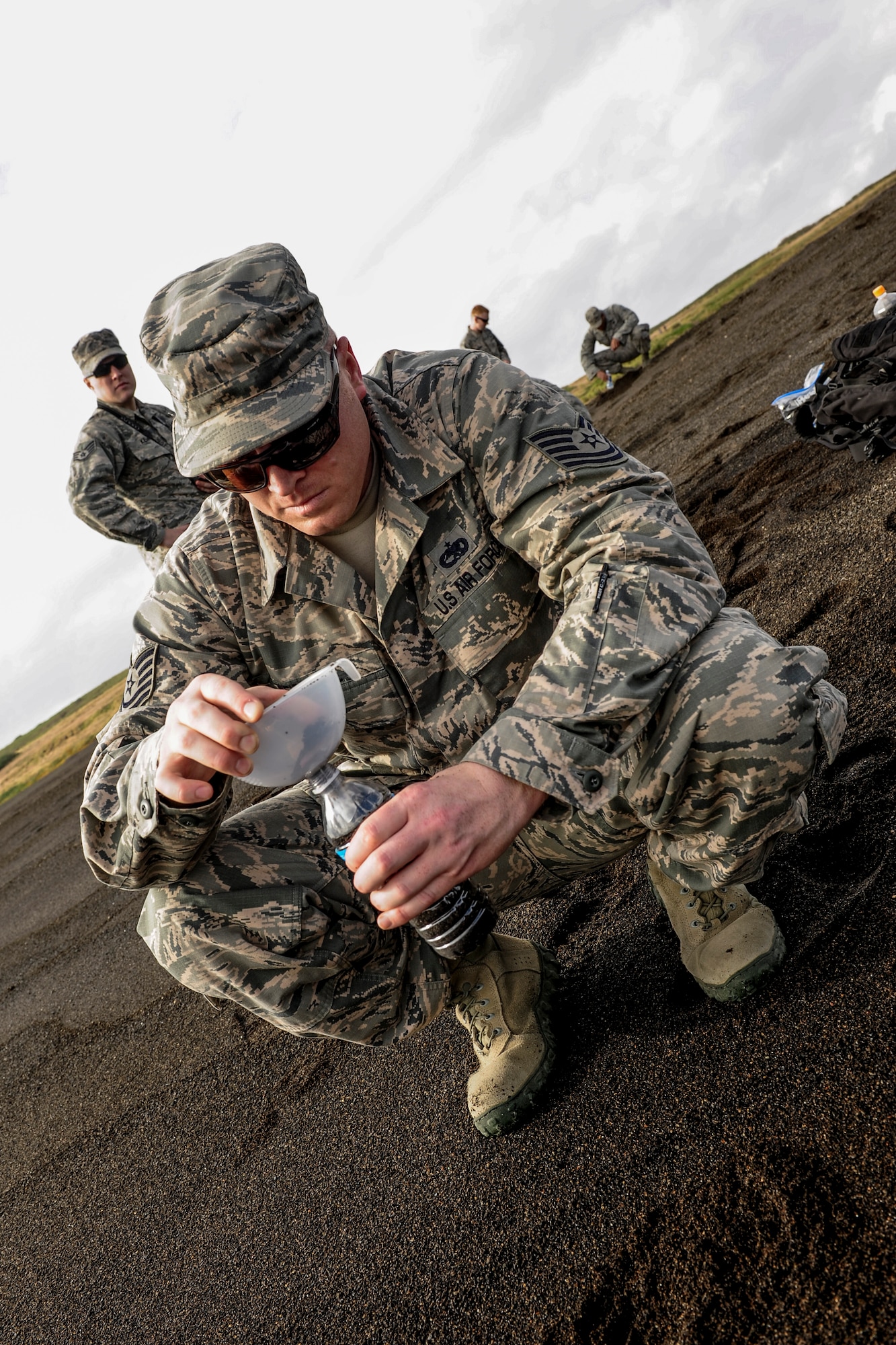 Tech. Sgt. Benjamin Weisensel, 733rd Air Mobility Squadron unit deployment manager, funnels sand into a bottle Jan. 8, 2015, on the shores of Iwo To, Japan. This is the location where thousands of Marines landed during the battle of Iwo Jima. (U.S. Air Force photo by Airman 1st Class John Linzmeier)