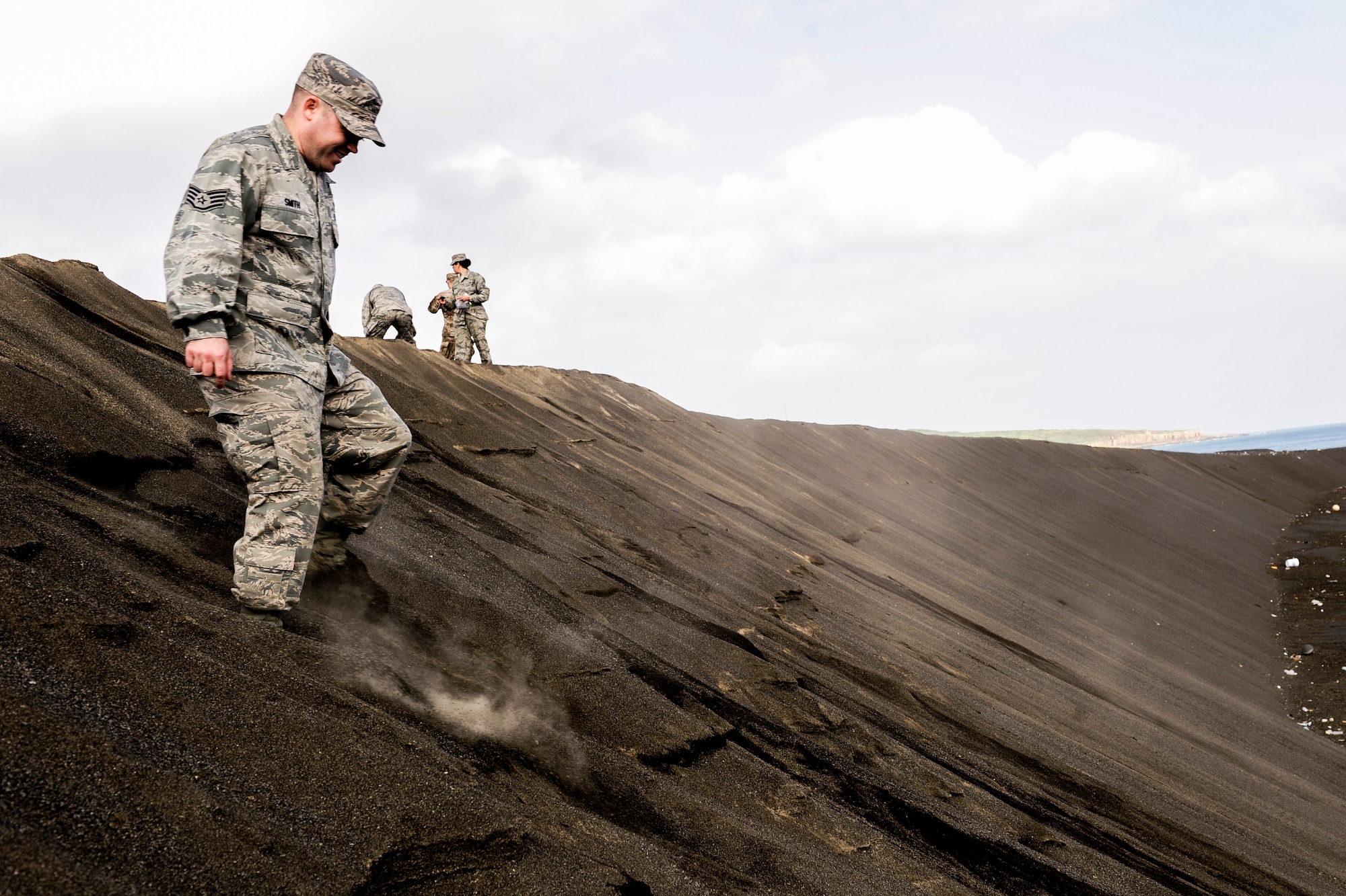U.S. Air Force Staff Sgt. Corey Smith, 733rd Air Mobility Squadron air fright supervisor, treads down a slope of sand toward the coast Jan. 8, 2015 on Iwo To, Japan. Members of Kadena Air Base, Japan, gathered handfuls of sand to serve as a reminder of the battle of Iwo Jima, which had taken place on the island nearly 70 years ago. (U.S. Air Force photo by Airman 1st Class John Linzmeier)