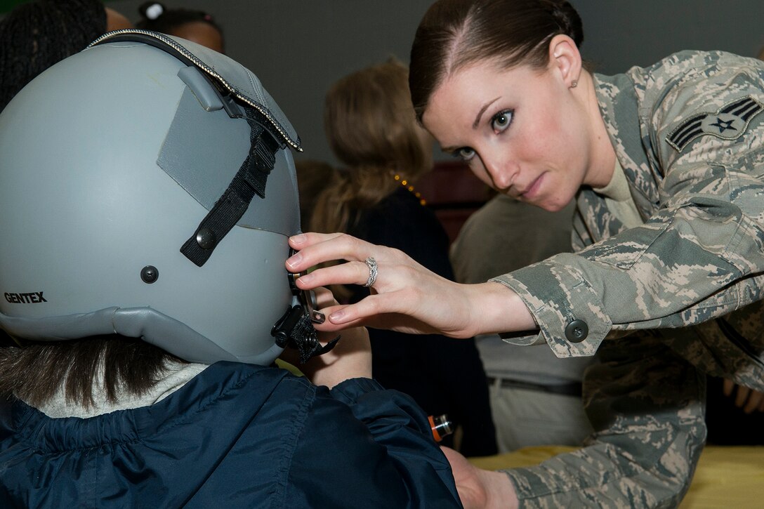 U.S. Air Force Senior Airman Meagan Kay, 307th Operations Support Squadron aircrew flight equipment technician, helps an Elm Grove Elementary student try on a helmet, Jan. 7, 2015, Bossier City, La. The 307th OSS was invited to participate in the school's Science, Technology, Engineering and Mathematics Career Day. (U.S. Air Force photo by Master Sgt. Greg Steele/Released)