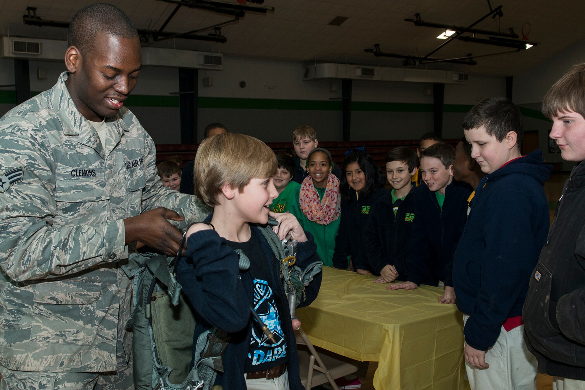 U.S. Air Force Senior Airman Trimaine Clemons, 307th Operations Support Squadron (OSS) aircrew flight equipment technician, helps an Elm Grove Elementary student try on a parachute, Jan. 7, 2015, Bossier City, La. The 307th OSS was invited to participate in the school's Science, Technology, Engineering and Mathematics Career Day. (U.S. Air Force photo by Master Sgt. Greg Steele/Released)