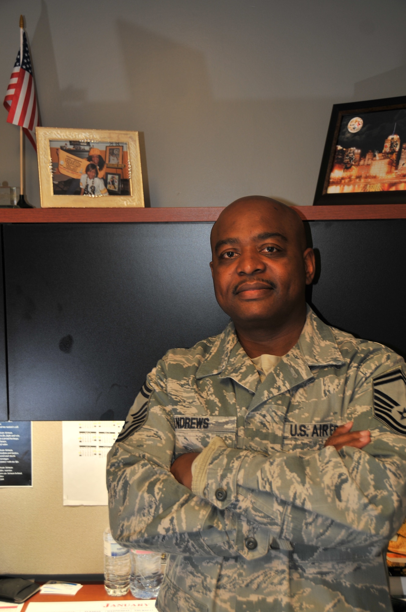 Senior Master Sgt. William Andrews, 911th Logistics Readiness Squadron superintendent, poses next to a photo of his two daughters in his office at the Pittsburgh International Airport Air Reserve Station, January 10, 2015. Andrews recently went above and beyond his civilian duty as a police officer to change the life of a young boy, stating that if he would want someone to look out for his child or grandchild, he would do the same for others. (U.S. Air Force photo by Senior Airman Marjorie A. Bowlden)