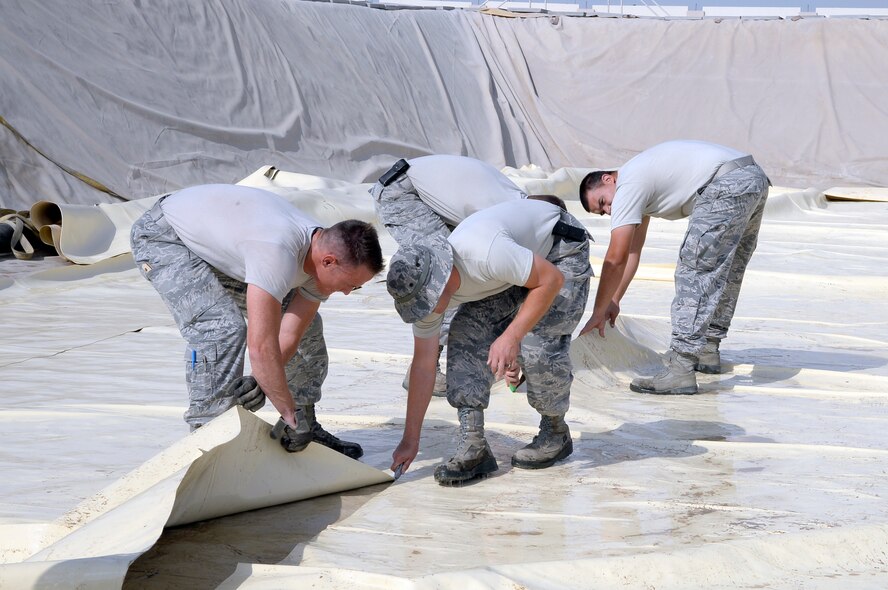 Airmen assigned to the Expeditionary Logistics Readiness Squadron fuels management flight cut and dispose of a fuel bladder inside a containment area at an undisclosed location in Southwest Asia Dec. 16, 2014. The bladder fuel storage facility holds and distributes all fuel used throughout the base. (U.S. Air Force photo/Tech. Sgt. Marie Brown) 