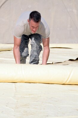 Senior Airman Daniel, fuel storage attendant, rolls up a piece of a fuel bladder inside a containment area at an undisclosed location in Southwest Asia Dec. 12, 2014. Airmen from the petroleum, oil and lubricants flight replaced a 4,500 pound bladder due to leaks and tears. Daniel is currently deployed from Nellis Air Force Base, Nev., and is a native of Arlington, Texas. (U.S. Air Force photo/Tech. Sgt. Marie Brown)