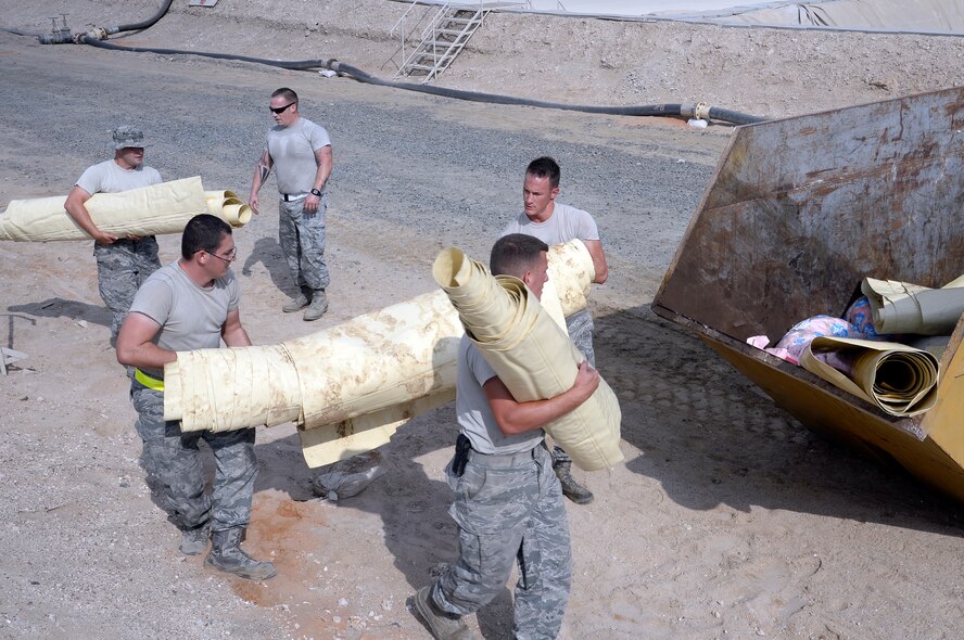 Airmen assigned to the Expeditionary Logistics Readiness Squadron fuels management flight dispose of a fuel bladder at an undisclosed location in Southwest Asia Dec. 16, 2014. The flight maintains, inspects and replaces equipment to ensure the mission can be accomplished safely. (U.S. Air Force photo/Tech. Sgt. Marie Brown)