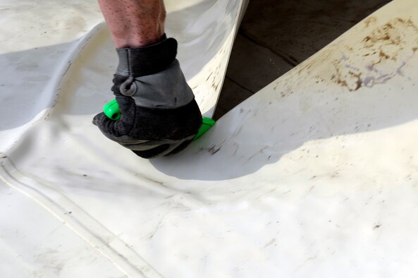 An Airman assigned to the Expeditionary Logistics Readiness Squadron cuts a fuel bladder at an undisclosed location in Southwest Asia Dec. 16, 2014. The fuel bladder was being replaced due to existing leaks and tears that were not able to be repaired. (U.S. Air Force photo/Tech. Sgt. Marie Brown)