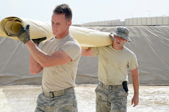 Senior Airmen Daniel, left, and Timothy, fuel storage attendants, carry a piece of a fuel bladder at an undisclosed location in Southwest Asia Dec. 12, 2014. The fuels management flight is responsible for receiving, storing and issuing clean, dry fuel and liquid oxygen. Daniel is currently deployed from Nellis Air Force Base, Nev. and is a native of Arlington, Texas. Timothy is currently deployed from Travis Air Force Base, Calif. and is a native of Gettysburg, Pa. (U.S. Air Force photo/Tech. Sgt. Marie Brown)