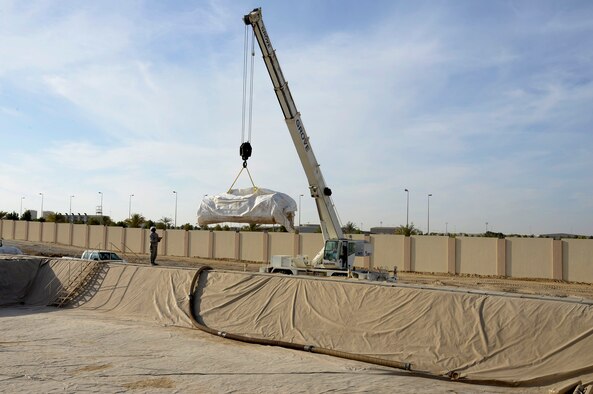 Members of the Expeditionary Civil Engineer Squadron prepare to drop a 4,500 pound fuel bladder inside a containment area at an undisclosed location in Southwest Asia Dec. 16, 2014. It took more than 30 individuals to roll out and position the bladder once in place. (U.S. Air Force photo/Tech. Sgt. Marie Brown)