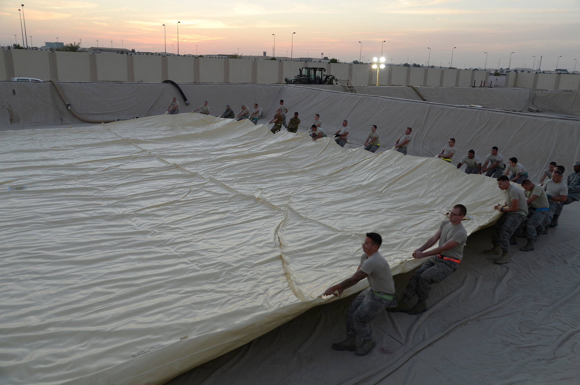 Airmen assigned to the Expeditionary Logistics Readiness Squadron fuels management flight position a 4,500 pound fuel bladder inside a containment area at an undisclosed location in Southwest Asia Dec. 16, 2014. Fuels Airmen offload up to 60 tank trucks per day of jet fuel and another 5-10 trucks of gasoline and diesel. (U.S. Air Force photo/Tech. Sgt. Marie Brown)
