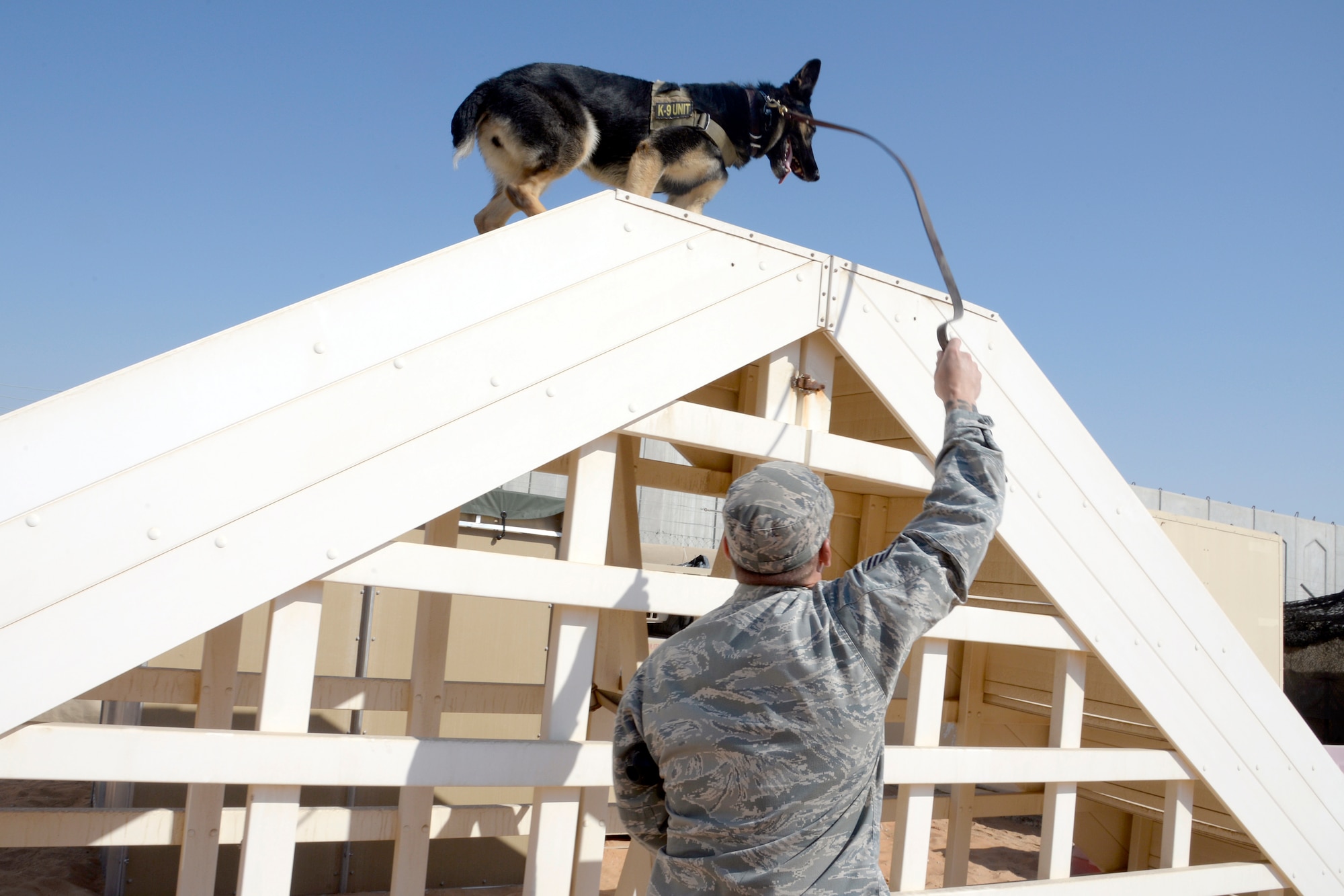 Staff Sgt. Justin, military working dog handler, runs his MWD Oxigen over the stairs a part of their obstacle course during an obedience training session at an undisclosed location in Southwest Asia Jan. 5, 2015. Receiving on average of at least 30 training sessions a month, the MWD teams train on as many realistic scenarios as possible. Justin is currently deployed from Fairchild Air Force Base, Wash., and is a native of Tamuning, Guam. (U.S. Air Force photo/Tech. Sgt. Marie Brown)