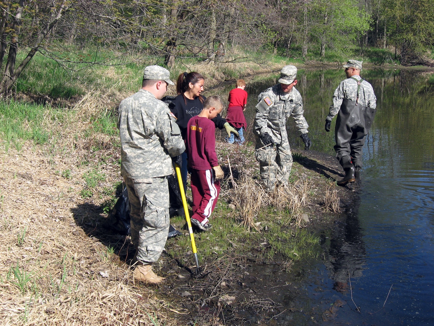 The 147th and 247th Finance Detachments of the Minnesota National Guard joined forces with local leaders to clean up their community in Roseville, Minn., April 18, 2010. The two finance units along with local residents picked up garbage, glass and other debris at local parks. Spc. Steven VanCourt, Cpl. Jason Mosher and Staff Sgt. Eric Stensvold, all of the 247th Finance Detachment, help dredge the lake.