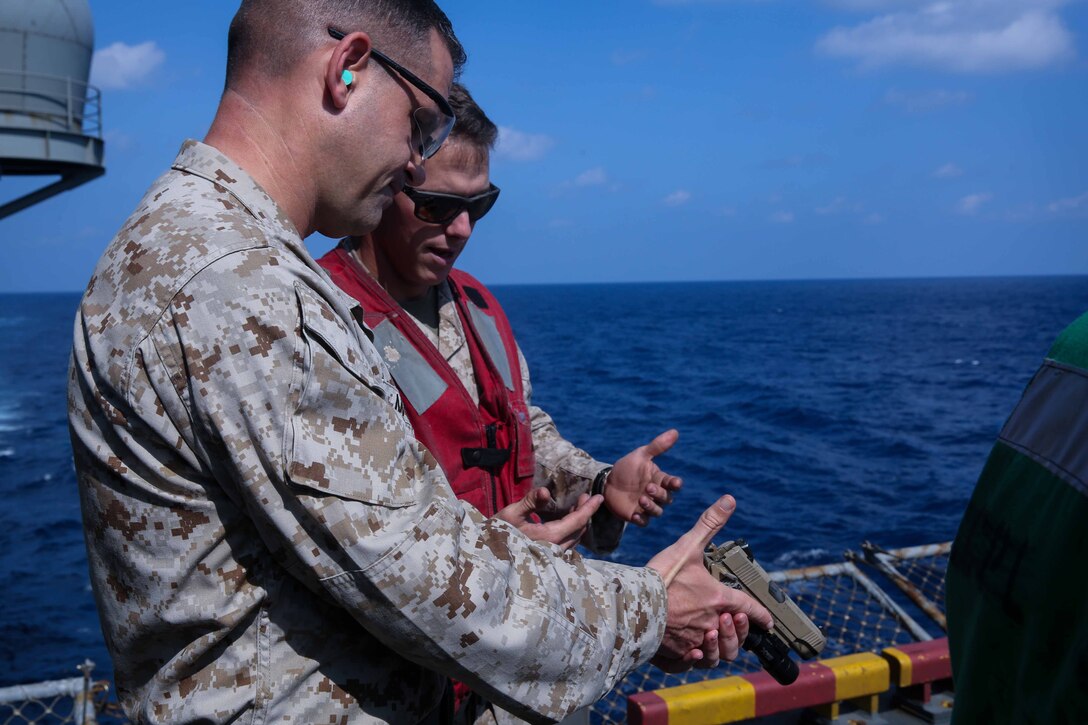 U.S. Marine Corps Lt. Col. Coby Moran, left, commanding officer, Battalion Landing Team 2nd Battalion, 1st Marines, 11th Marine Expeditionary Unit (MEU), reviews weapon manipulations as part of a pistol range aboard the amphibious assault ship USS Makin Island (LHD 8), Jan. 8, 2014. The 11th MEU is deployed with Makin Island Amphibious Ready Group as a theater reserve and crisis response force throughout U.S. Central Command and 5th Fleet area of responsibility. (U.S. Marine Corps photo by Cpl. Evan R. White/Released)