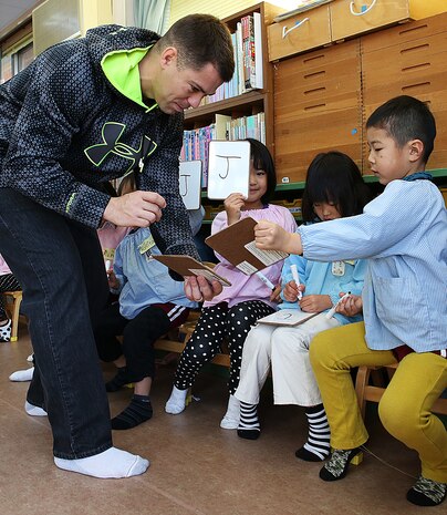 Staff. Sgt. John Skehan, family readiness officer for Combat Logistics Company 36 aboard Marine Corps Air Station, Iwakuni, Japan, shows students of Kinnan Hoikuen in Iwakuni city, how to write out letters of the English alphabet during a community relations visit, Jan. 9, 2015. Marines from CLC-36 visited the school to teach basic English, interact with the Japanese children and play popular American games.