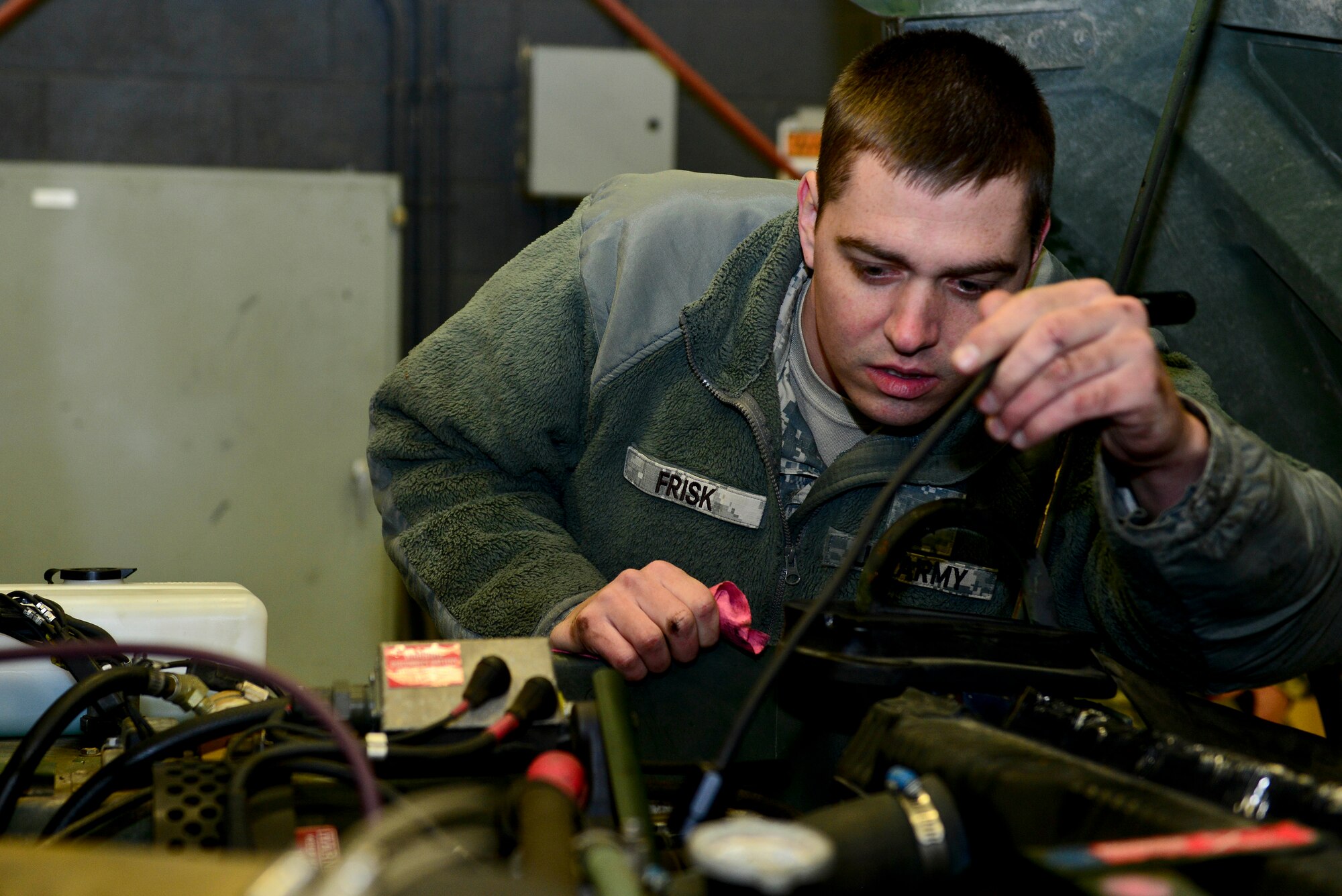 U.S. Army Cpl. Christopher Frisk, 155th Inland Cargo Transfer Company, 53rd Transportation Battalion (Movement Control), 7th Transportation Brigade (Expeditionary) wheel vehicle mechanic, checks for possible leaks in a Humvee at the 155th ICTC motor pool at Fort Eustis, Va., Jan. 7, 2015. Motor pool components, such as Humvees and generators, are used for deployments, local missions and training. (U.S. Air Force photo by Senior Airman Kimberly Nagle/Released)
