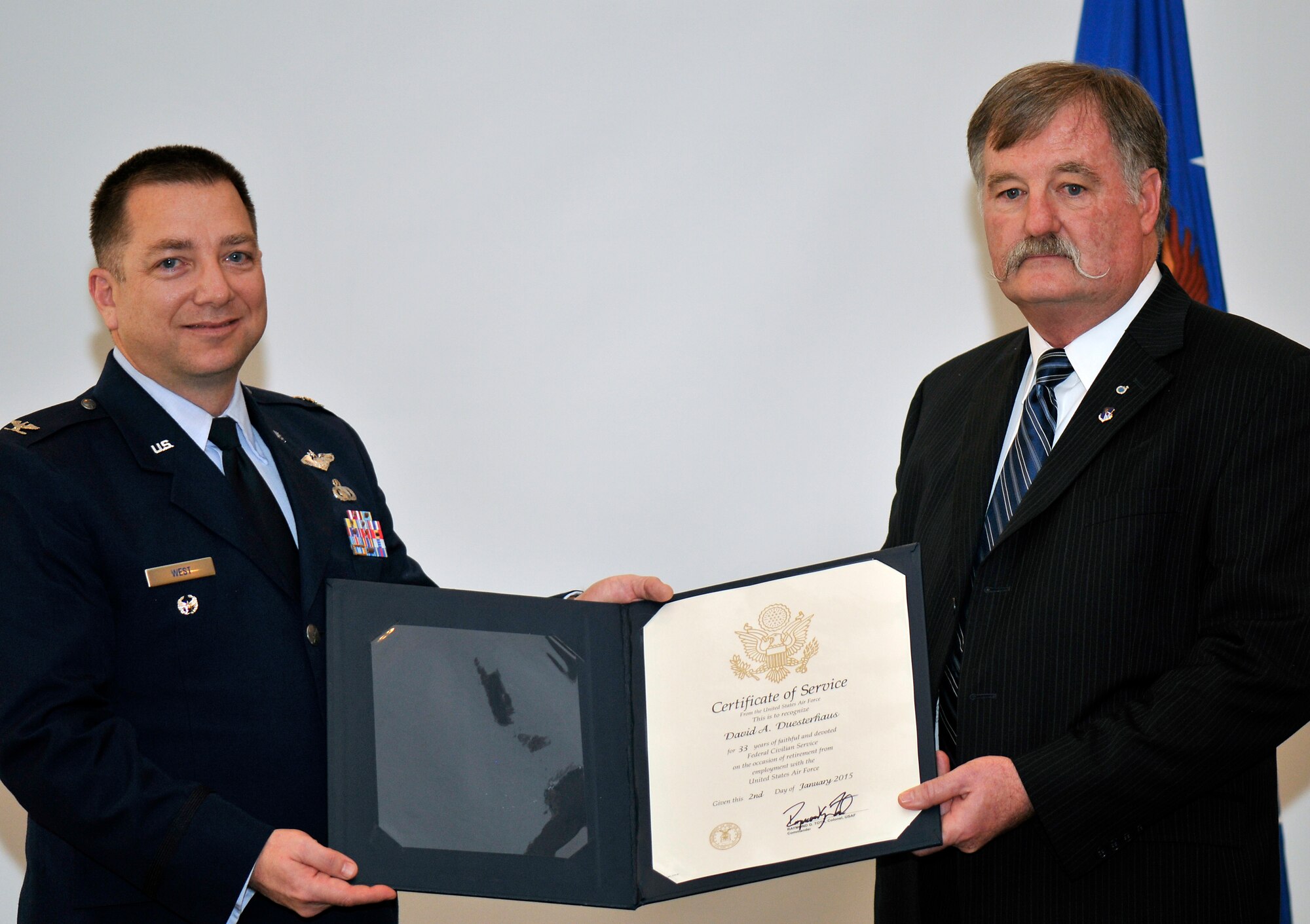 Dave Duesterhaus, right, receives a Certificate of Service from the United States Air Force for 33 years of federal civilian service during his retirement ceremony at AEDC on Dec. 17. Duesterhaus’s career at AEDC spans 42 years as a contract and civilian employee. While at AEDC he served as the first U.S. Air Force director for the National Full-Scale Aerodynamic Complex (NFAC) at the NASA Ames Research Center, Moffett Field, Calif. He retires as the chief of the Test Technology Branch with the AEDC Test Operations Division. Immediate family members in attendance include Duesterhaus’s wife Debra, sons Scott Duesterhaus and Trenton Bussell, and daughter Angela Byford. Pictured with Duesterhaus is Col. Timothy West, the AEDC Test Operations Division director, who served as the retiring official. (Photo by Jacqueline Cowan)