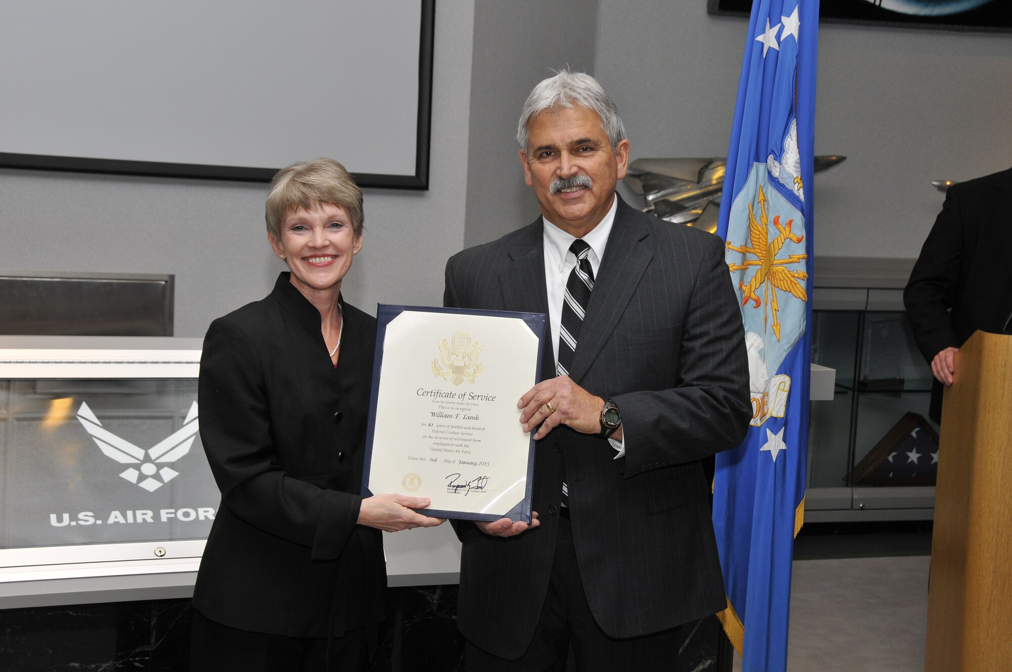 Bill Lamb, right, receives a Certificate of Service from the United States Air Force for 41 years of federal civilian service during his retirement ceremony at AEDC on Dec. 16. Lamb retired as the deputy director of the Air Force Test Center Contracting Division (AFTC/PZ) at Arnold Air Force Base. Immediate family members in attendance include Lamb’s wife Deborah, sons Shane and Brandon, and daughters Tiffany and Chelsea. Amy Foster, the director of the Arnold AFTC/PZ, is shown presenting the Certificate of Service to Lamb. (Photo by Rick Goodfriend)