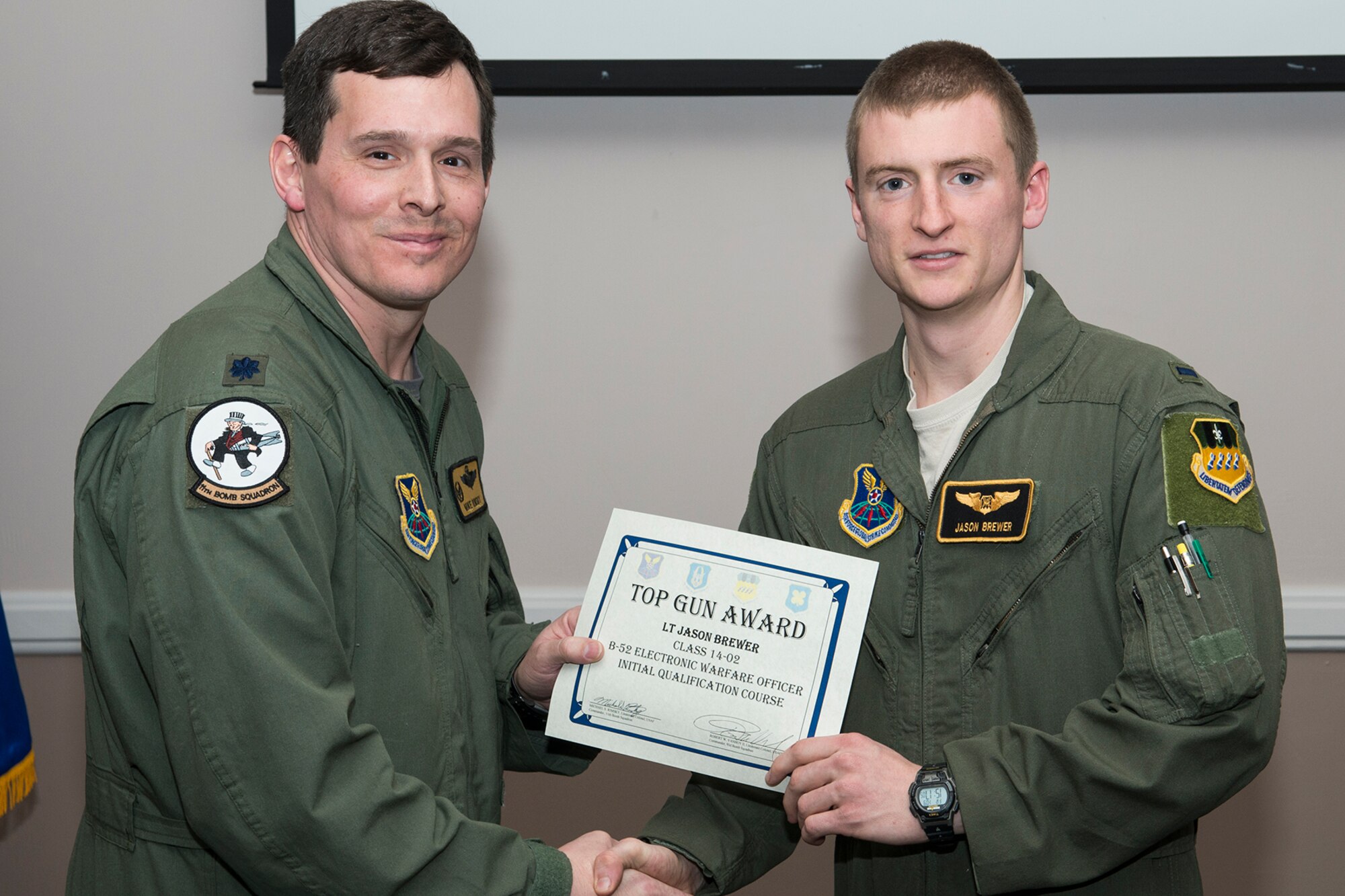 U.S. Air Force Lt. Col. Michael Rimsky, 11th Bomb Squadron commander, presents the Top Gun Electronic Warfare Officer (EWO) Award to 1st Lt. Jason Brewer during a graduation ceremony, Jan. 9, 2015, Barksdale Air Force Base, La. The award is given to the EWO who demonstrates exceptional threat counter-tactics and equipment operations in a simulated multiple-threat environment designed to test the individual in all aspects of electronic warfare. (U.S. Air Force photo by Master Sgt. Greg Steele/Released)