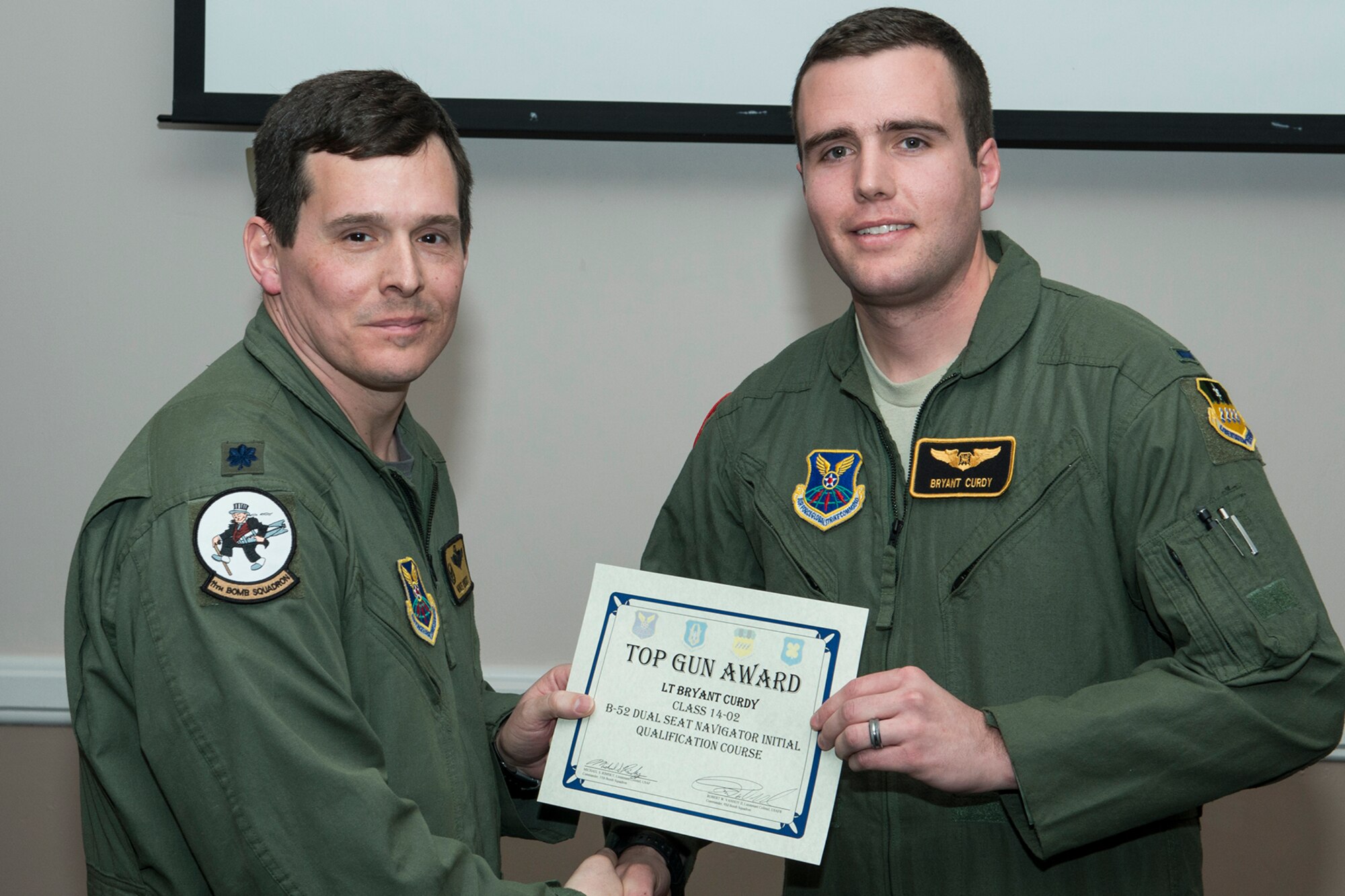 U.S. Air Force Lt. Col. Michael Rimsky, 11th Bomb Squadron commander, presents the Top Gun Dual Seat Navigator Award to 1st Lt. Bryant Curdy during a graduation ceremony, Jan. 9, 2015, Barksdale Air Force Base, La. The award is given to the navigator that demonstrates the best time-on-target control skill incorporating both a live weapons drop and a simulated dynamic combat environment. (U.S. Air Force photo by Master Sgt. Greg Steele/Released)