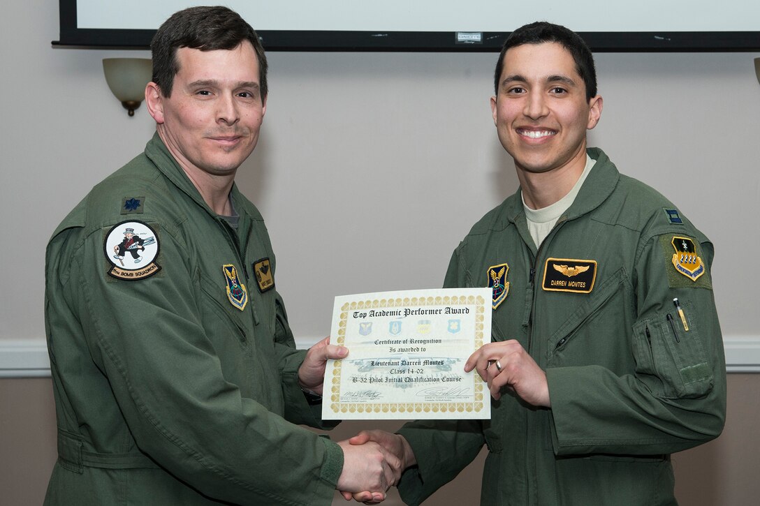 U.S. Air Force Lt. Col. Michael Rimsky, 11th Bomb Squadron commander, presents the Top Academic Performer Award to Capt. Darren Montes during a graduation ceremony, Jan. 9, 2015, Barksdale Air Force Base, La. Montes is a student of the B-52 Formal Training Unit class 14-02 and graduated with the highest academic scores in the Initial B-52 Pilot Qualification course. (U.S. Air Force photo by Master Sgt. Greg Steele/Released)