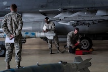 Tech. Sgt. Thomas Anderson (far left), 8th Maintenance Group weapons standardization crew member, evaluates Staff Sgt. Trumaine Cox and Senior Airman Benjamin Wilsey, 80th Aircraft Maintenance Unit weapons load crew 40 members, during the fourth quarter weapons loading competition Jan. 9, 2015, at Kunsan Air Base, Republic of Korea. With just an 11-point lead, Cox, Wilsey, and Senior Airman Gavin Moses were named the winners. (U.S. Air Force photo by Senior Airman Katrina Heikkinen/Released)