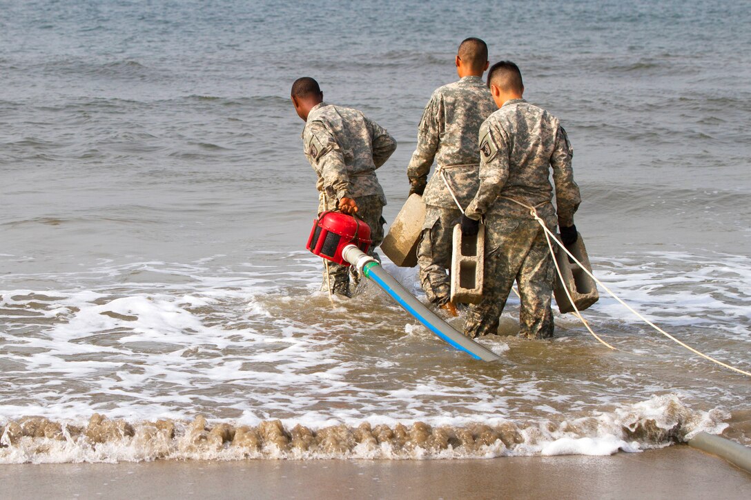 U.S. Army Sgt. Musa Conteh, from left, Pfc. Tieyu Zhang and Pfc. Oscar Ortiz employ a tactical water purification system at a waterfront in Buchanan, Liberia, Jan. 8, 2015. The purification system provides clean water for forces supporting Operation United Assistance. The soldiers are assigned to the 227th Quartermaster Company, 129th Combat Sustainment Support Battalion, 101st Sustainment Brigade, Task Force Lifeliners, Joint Task Force - United Assistance. 