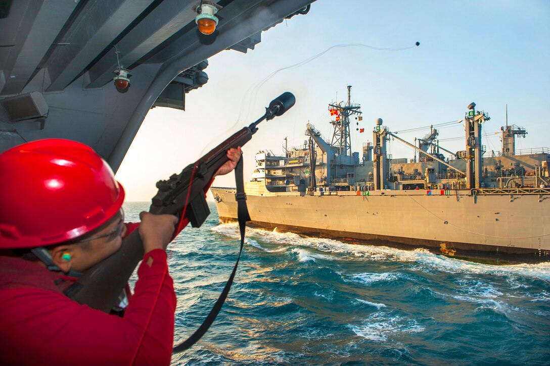 U.S. Navy Seaman Jon Reolizo fires a shot line from an M14 rifle aboard the aircraft carrier USS Carl Vinson during a replenishment at sea with the Military Sealift Command fast combat support ship USNS Rainier in the U.S. 5th Fleet area of responsibility, Jan. 7, 2015. Reolizo is an aviation ordnanceman airman.