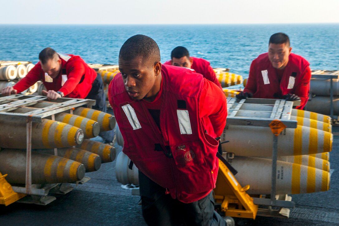 U.S. Navy Seaman Cameron Rogers and fellow aviation ordnancemen haul ordnance off an aircraft elevator aboard the aircraft carrier USS Carl Vinson during a replenishment at sea with the Military Sealift Command fast combat support ship USNS Rainier in the U.S. 5th Fleet area of responsibility, Jan. 7, 2015. 
