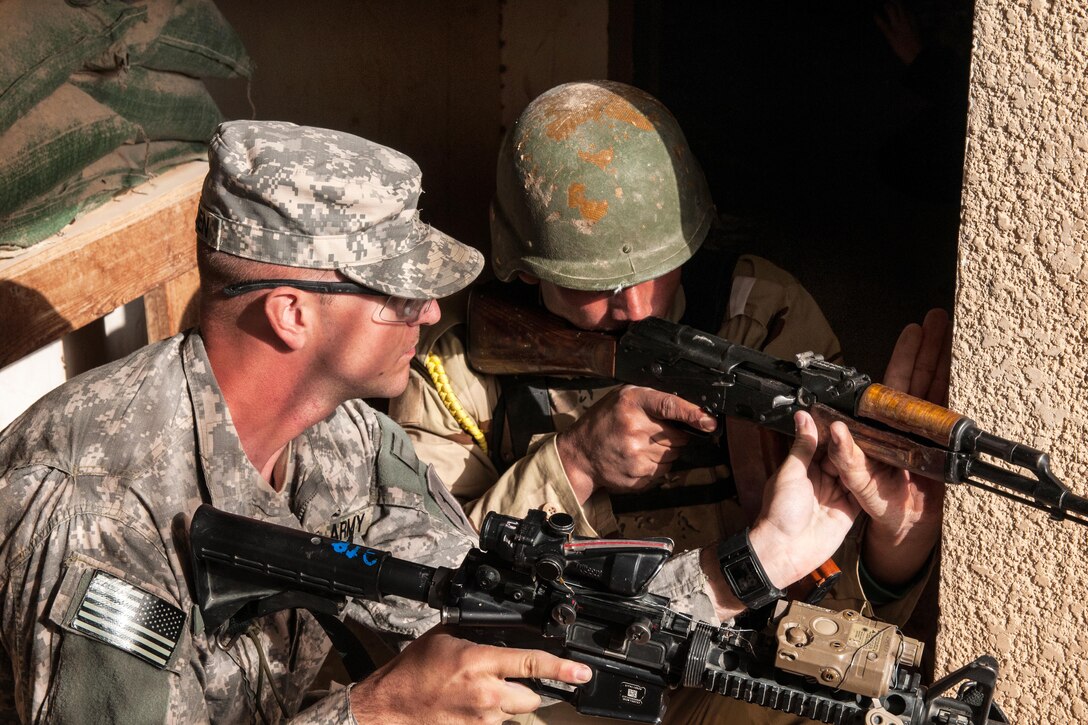 U.S. Army Sgt. Jeremiah Walden, left, adjusts an Iraqi army trainee's weapon to ensure he's covering the correct sector of fire during infantry squad tactical training on Camp Taji, Iraq, Jan. 7, 2015. Walden is an infantry trainer assigned to the 1st Infantry Division's Company A, 2nd Battalion, 34th Armor Regiment, 1st Armored Brigade Combat Team.