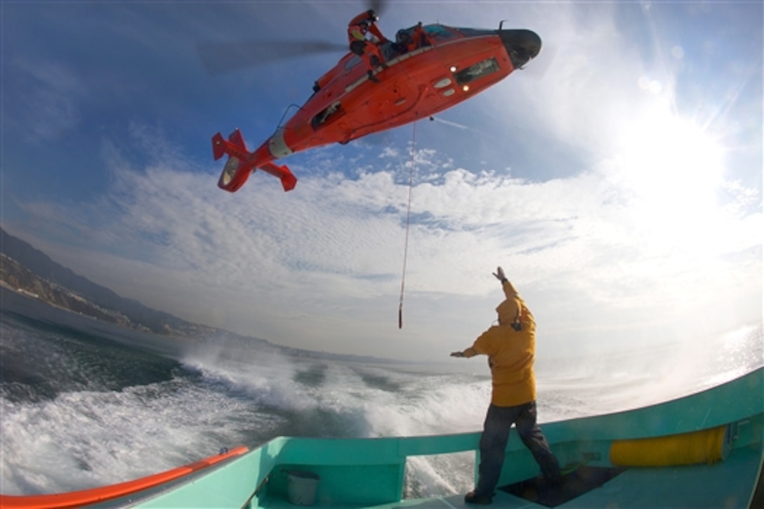 A lifeguard prepares to receive a rescue basket from the crew of a Coast Guard MH-65D helicopter during a training exercise off the coast of Malibu, Calif., Jan. 9, 2015.The Coast Guard crew is assigned to Air Station Los Angeles.