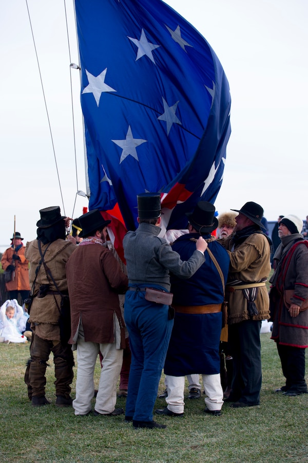 Volunteers reenacting as American militiamen in the War of 1812 catch the flag as it is lowered at the Jean Lafitte National Historic Park and Preserve Jan. 10, 2015. The park hosted a series of living history events on the Chalmette Battlefield in Chalmette, La., that commemorated the bicentennial 1815 Battle of New Orleans.