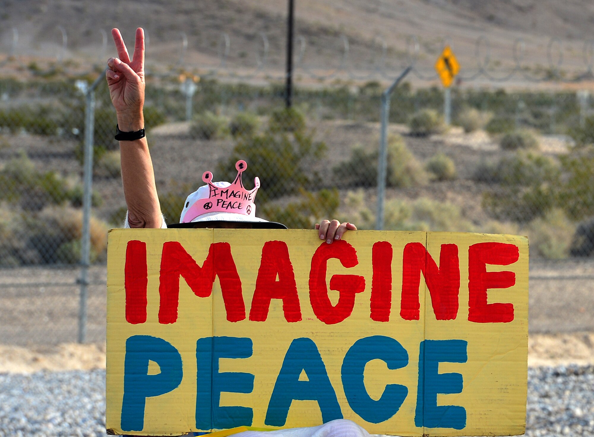 A Code Pink protester sits outside the gates of Creech Air Force Base, Nevada during a peaceful anti-remotely piloted aircraft demonstration April 11, 2014. During the demonstration, anti-war songs were played and skits were acted out by the protesters. (U.S. Air Force photo by Staff Sgt. Nadine Barclay/Released)