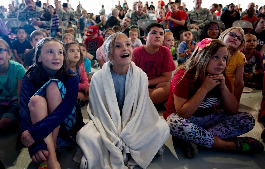 Children attending the Creech hosted Take Our Daughters and Sons to Work Day, sit and watch a magic show April 24, 2014 on Creech Air Force Base, Nev. During the day's events the Creech Airmen and Family Readiness Center provided a plethora of events including demonstrations from the local fire department, work center tours, and a professional magician and DJ. (U.S. Air Force photo by Staff Sgt. Adawn Kelsey/Released)