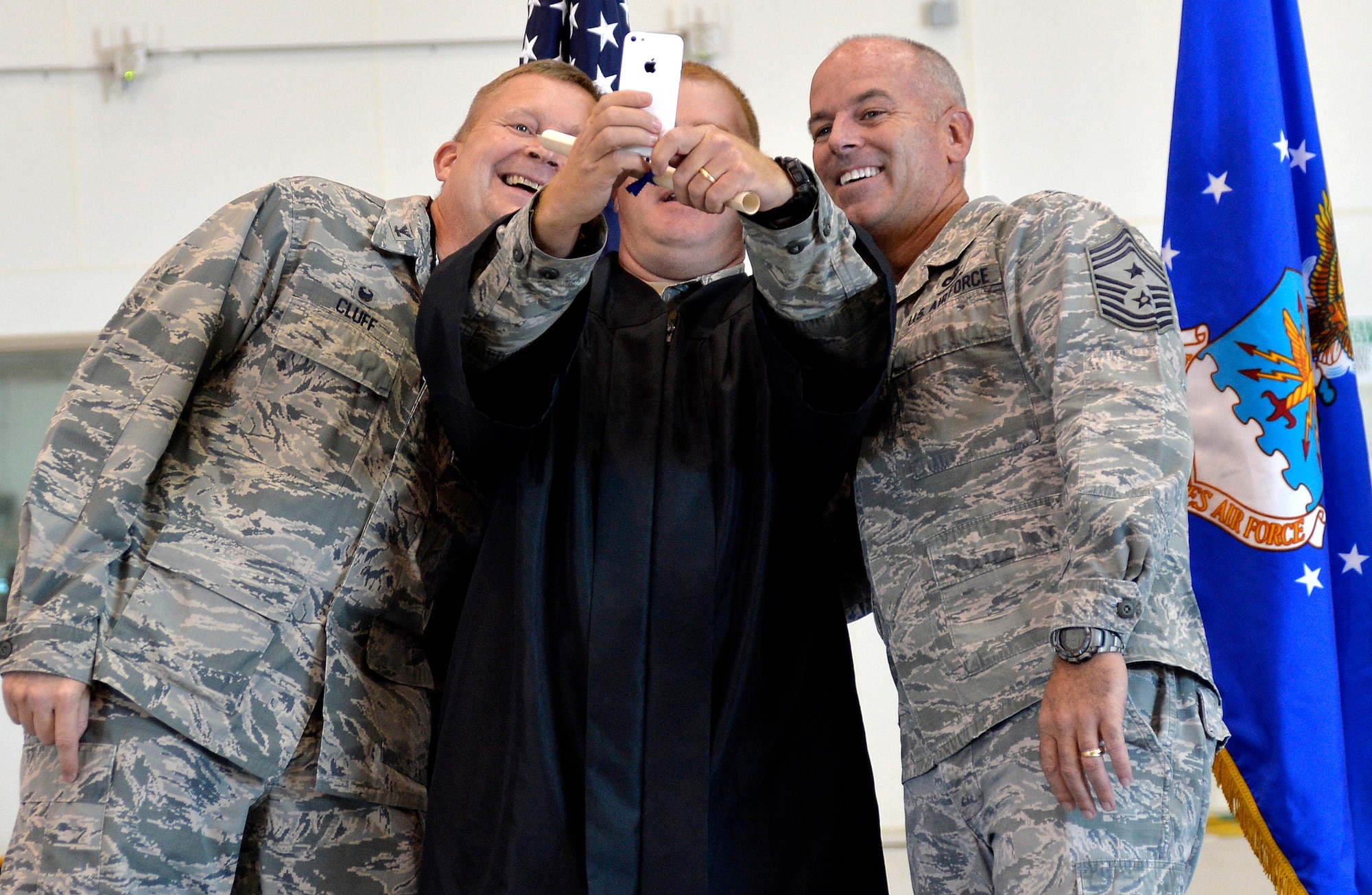 Master Sergeant Bryan Teeples, 15th Reconnaissance Squadron first sergeant, takes a selfie with Col. James Cluff, 432nd Wing/432nd Air Expeditionary Wing commander, and Chief Master Sergeant Butch Brien, 432nd WG/432nd AEW command chief, at Creech Air Force Base’s first-ever Community College of the Air Force graduation, which took place on base Nov. 14, 2014. Combined, Nellis and Creech Air Force Bases have more than 400 Airmen who received diplomas during the fall CCAF graduating class. (U.S. Air Force photo by Staff Sgt. Adawn Kelsey/Released)