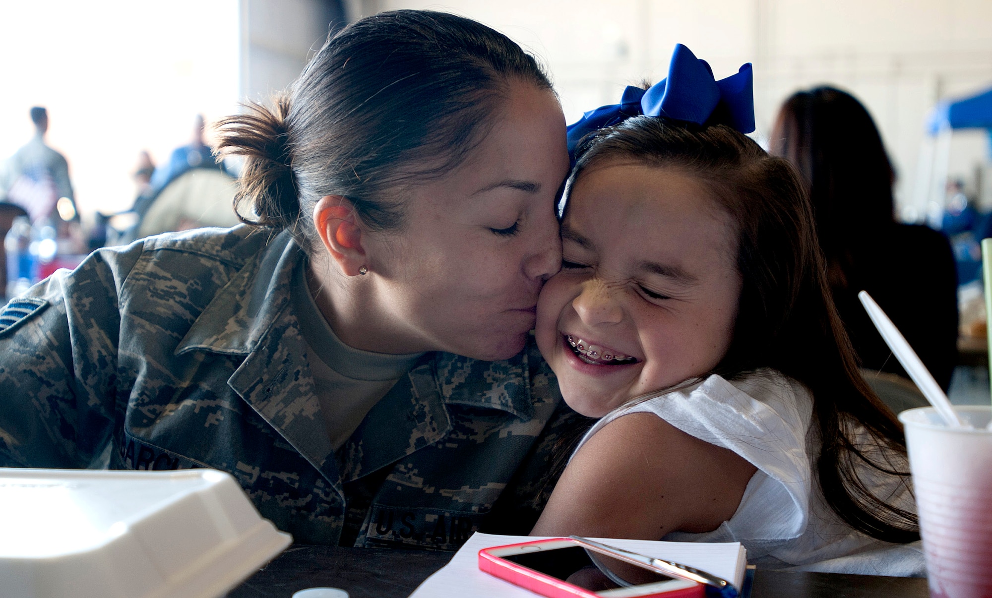 Staff Sgt. Nadine Barclay, 432nd Wing/432nd Air Expeditionary Wing Public Affairs NCO in charge kisses her daughter during the first Take Our Daughter and Sons to Work Day April 24, 2014, at Creech Air Force Base, Nevada. During the day's events the Creech Airmen and Family Readiness Center provided a plethora of events including demonstrations from the local fire department, work center tours, and a professional magician and DJ. (U.S. Air Force photo by Staff Sgt. Adawn Kelsey/Released)
